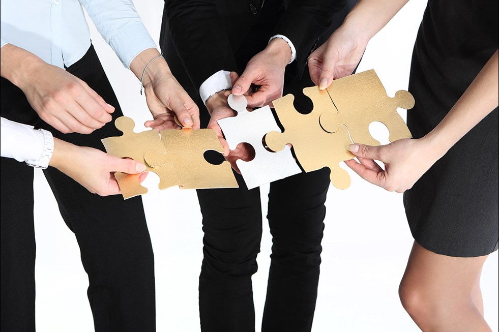 Grupa ludzi prezentuje srebrno złote puzzle